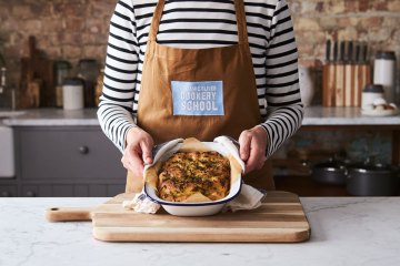 a person holding a baked focaccia in a baking tray