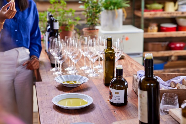 Table with wine bottles, glasses, and olive oil in a kitchen setting.