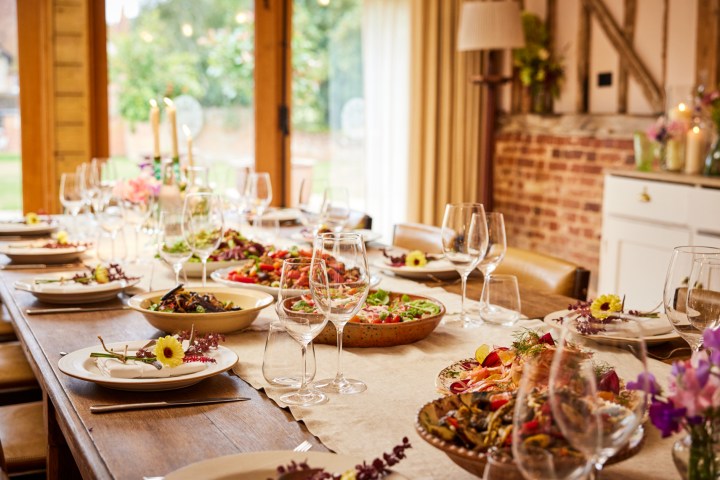Elegant dining table set with dishes, empty wine glasses, and flowers.