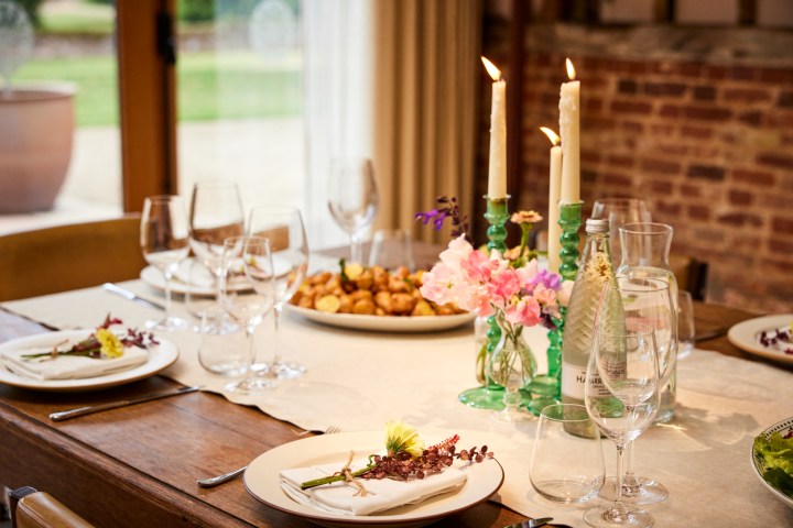 Elegant dining table setup with candles, flowers, plates, and glasses.