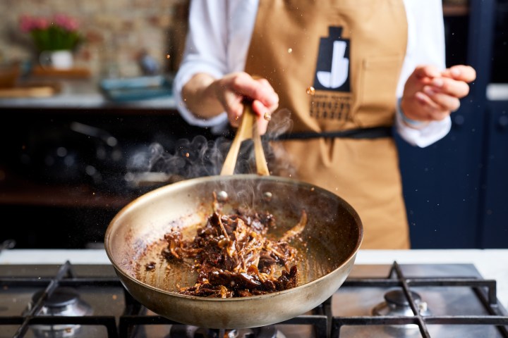 a person cooking food in a pan on a stove