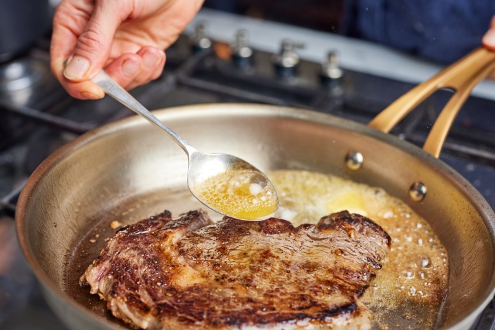a person cooking food on a metal pan on a stove