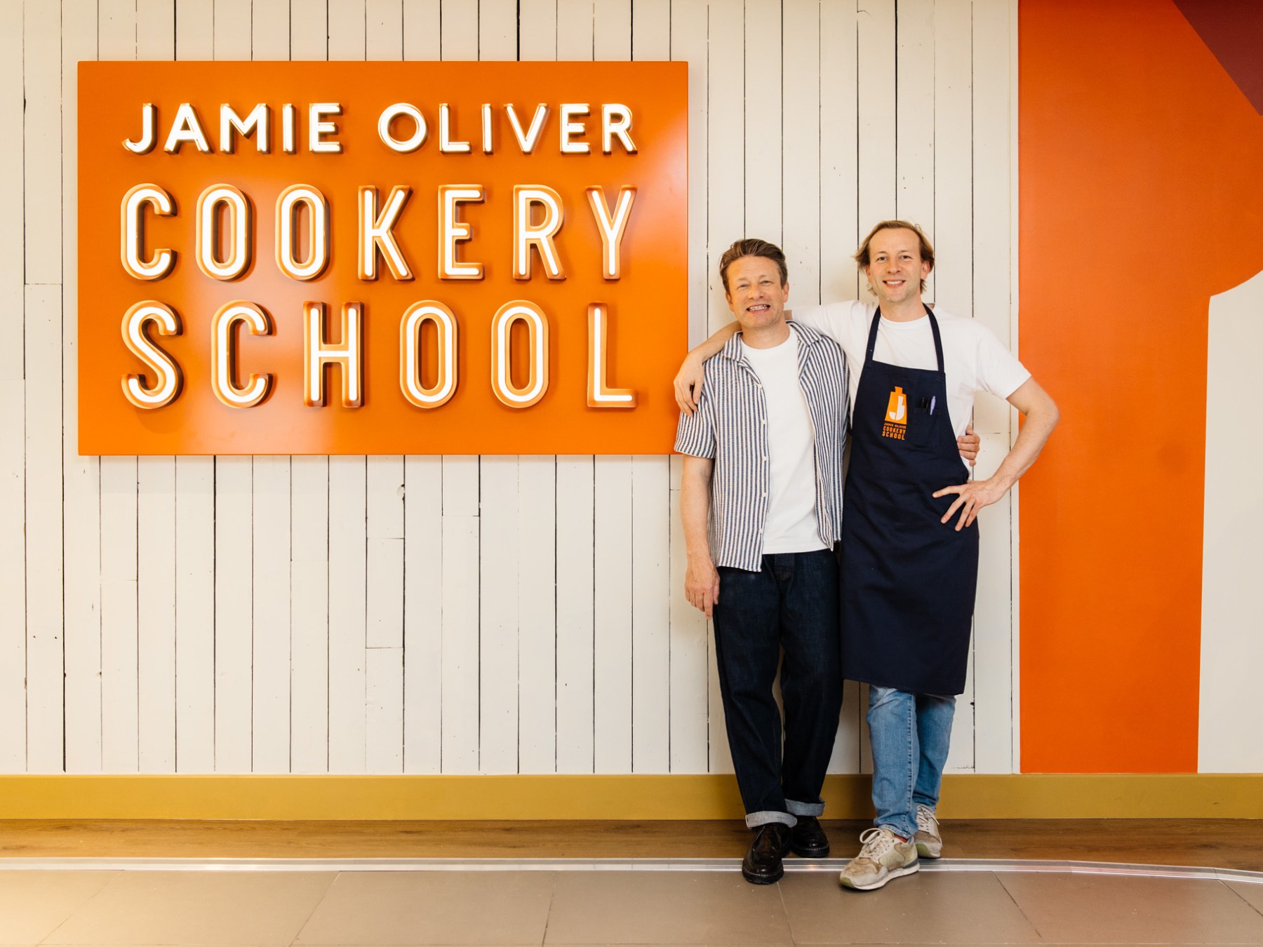 Jamie Oliver standing in front of a sign