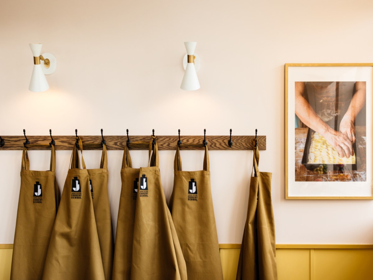 Brown aprons hanging on hooks, framed photo, and two white wall lights.
