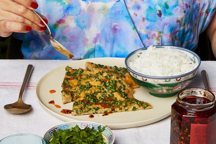 Person in colorful shirt eating rice and herb omelette.