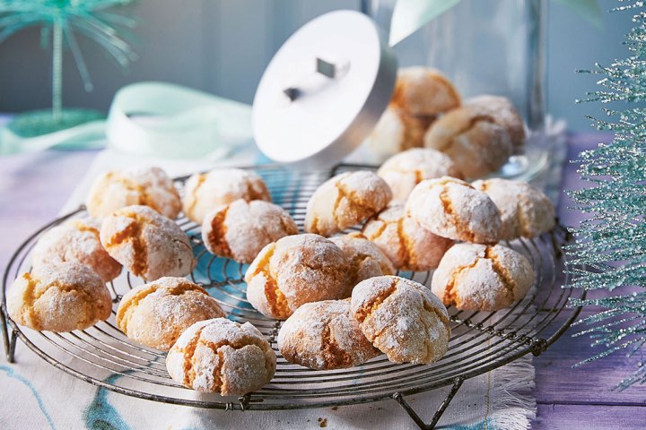 Powdered sugar crinkle cookies on a wire rack with festive decorations.