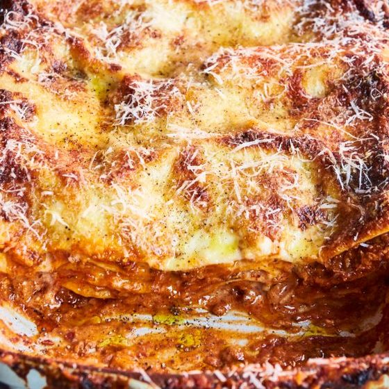 A freshly baked lasagna with one slice removed in a white baking dish.