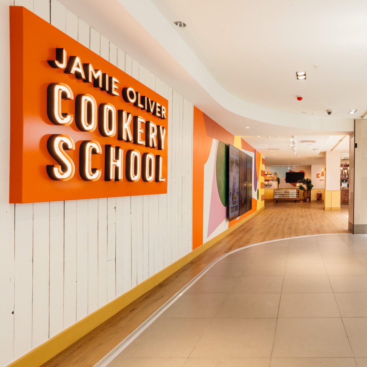 web__002__jamie-oliver-cookery-school-launch__interiors Interior of Jamie Oliver Cookery School with a large sign and modern decor.