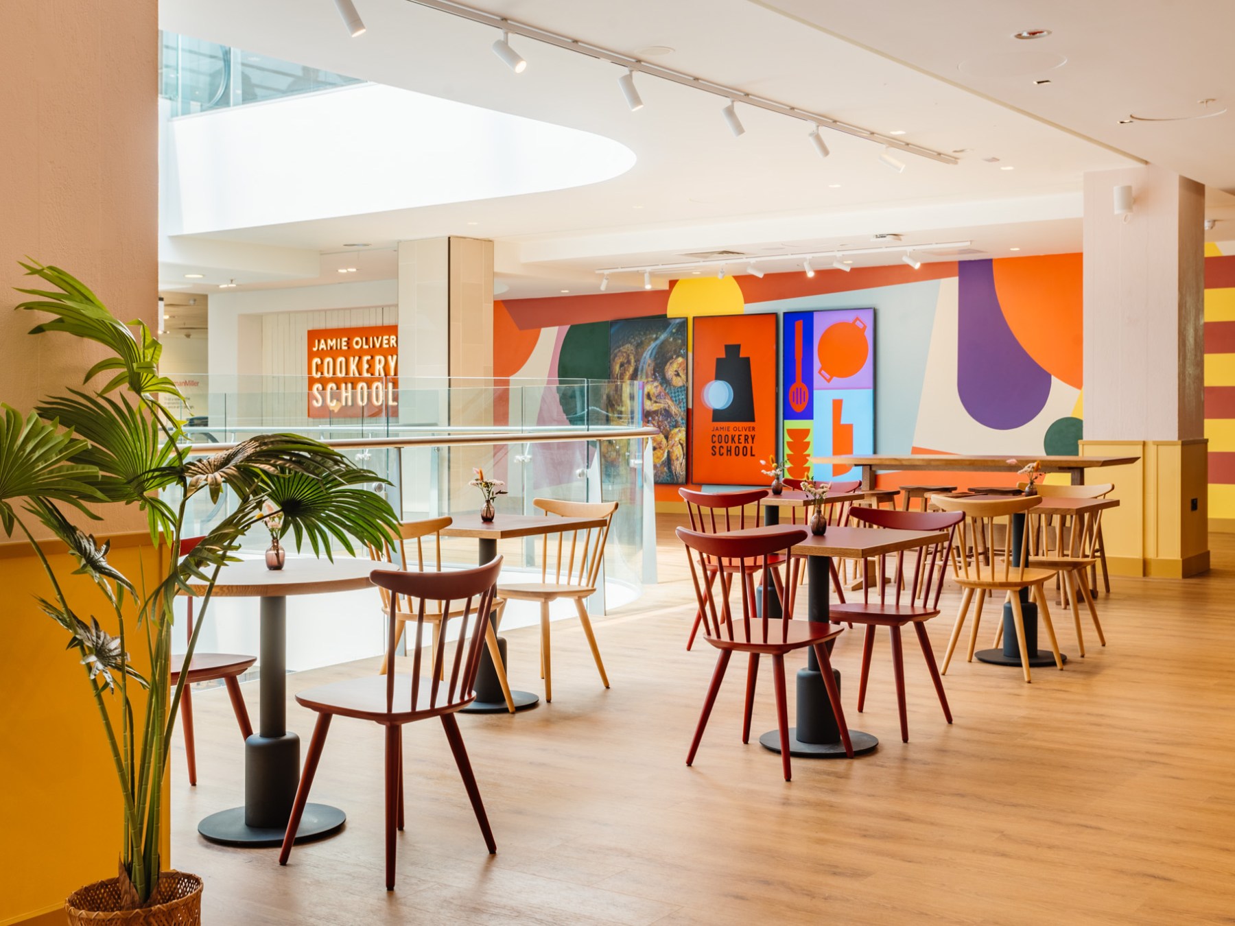 Colorful dining area with round tables, chairs, and bright artwork on the walls.