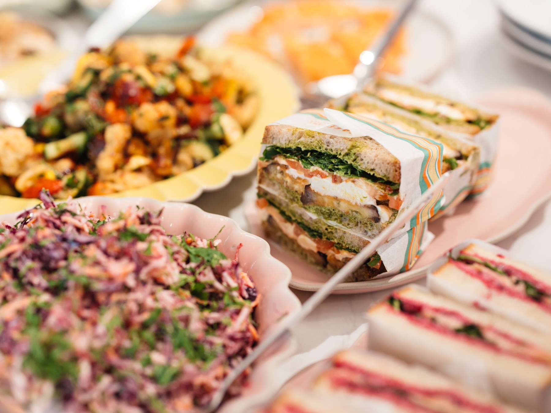 Variety of sandwiches and salads on a table with colorful plates.