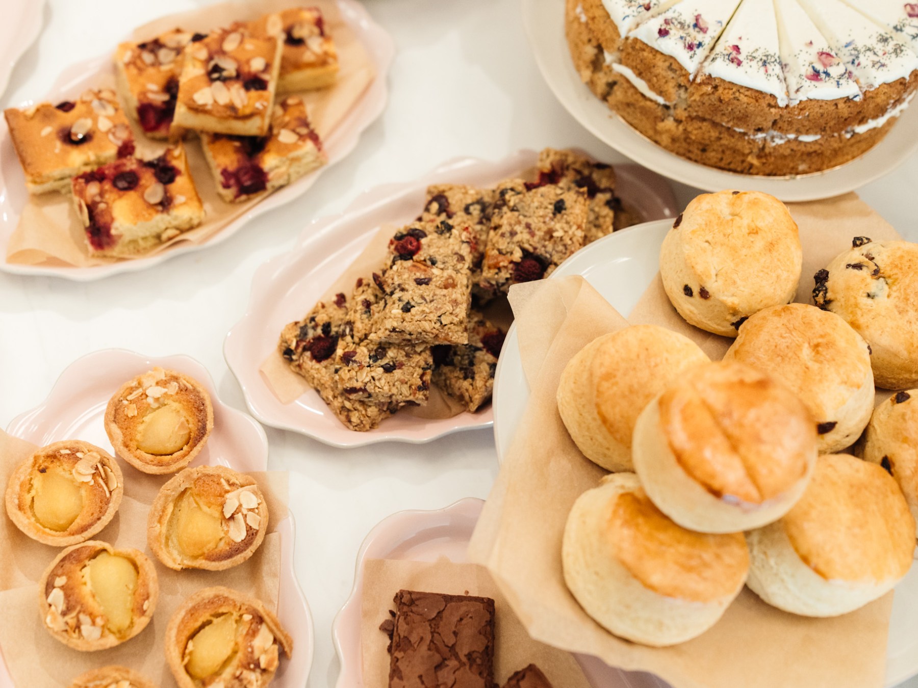 Assorted baked goods including scones, cake, bars, and small tarts on display.