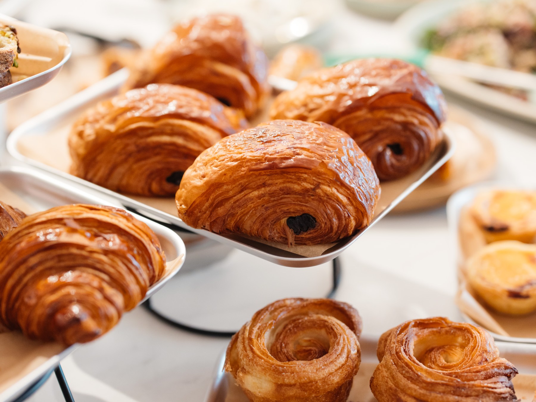 Assortment of pastries including croissants and rolls on trays.