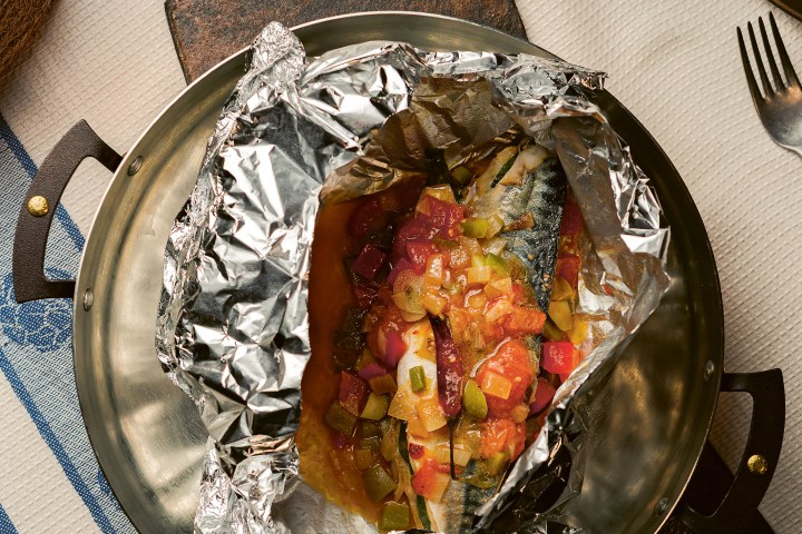 Baked fish with vegetables in foil on a plate.