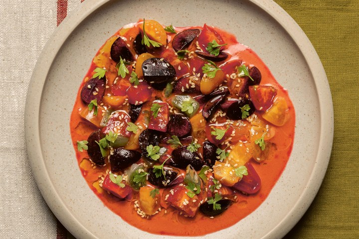 Plate of colorful beet salad on a green tablecloth with cutlery.