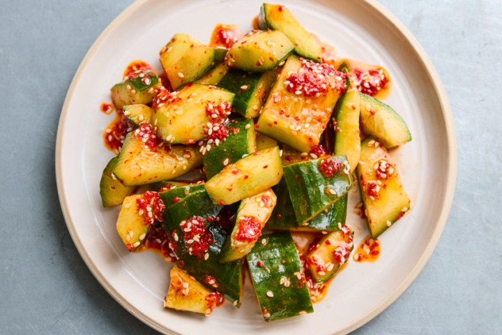 Plate of spicy cucumber salad with chili flakes on a white plate.