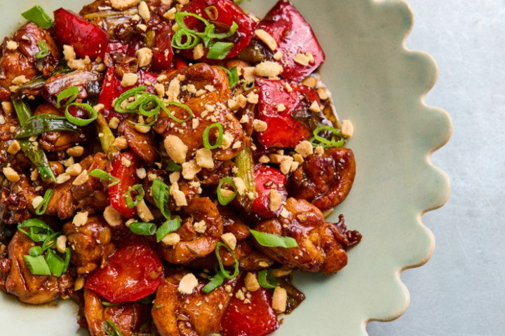 Colorful stir-fry with chicken, vegetables, and peanuts on a scalloped-edge plate.