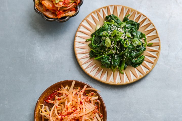 Three Korean side dishes on a gray surface.
