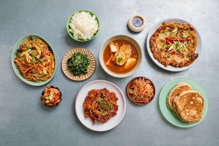 Assorted Korean dishes on a gray table, including pancakes and rice.